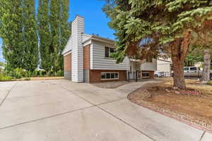 Bi-level home with brick and siding, concrete driveway, and a chimney