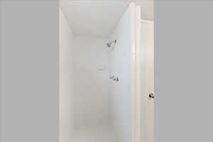 Bathroom with a textured ceiling and tiled shower