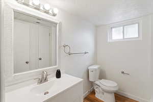 Bathroom featuring a textured ceiling, vanity, and wood finished floors