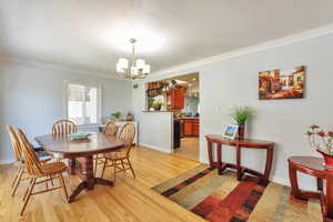 Dining area with ornamental molding, light wood-type flooring, a chandelier, and a textured ceiling