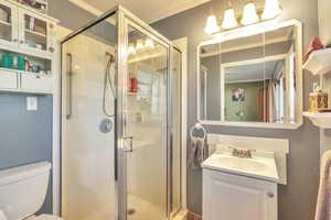 Bathroom with crown molding, a shower stall, and vanity