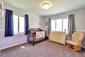 Carpeted bedroom with baseboards and a crib