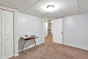 Finished basement with a paneled ceiling and carpet floors