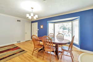 Dining space featuring crown molding, light wood-type flooring, and a chandelier
