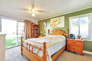 Bedroom with access to outside, light colored carpet, ornamental molding, and ceiling fan