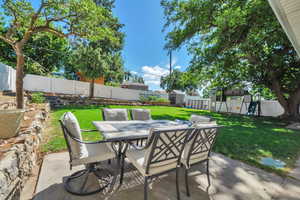 Fenced backyard featuring a storage unit, a patio, outdoor dining space, and a playground