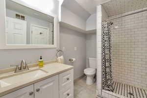 Full bathroom with vanity, a stall shower, tile patterned flooring, and vaulted ceiling