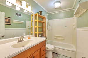 Full bath featuring wainscoting, ornamental molding, vanity, and shower / tub combination