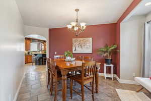 Dining space with arched walkways, a chandelier, and light stone finish floors