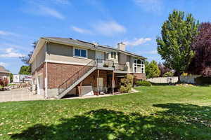 Back of property with solar panels, driveway, brick siding, stairway, and a chimney