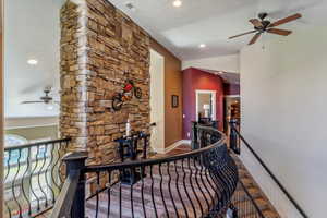 Corridor with an upstairs landing, lofted ceiling, and recessed lighting