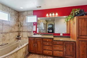 Bathroom with a stall shower, double vanity, a bath, and recessed lighting