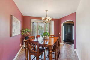 Dining room featuring arched walkways and a chandelier