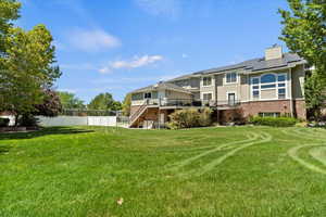 Rear view of property featuring stairway, roof mounted solar panels, a wooden deck, brick siding, and stucco siding