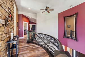 Hall featuring lofted ceiling, wood finished floors, an upstairs landing, and recessed lighting