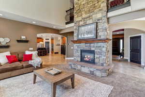Living room with recessed lighting, arched walkways, a fireplace, a high ceiling, and light tile patterned floors