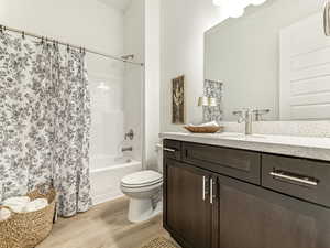 Full bath with shower / bathtub combination with curtain, vanity, and light wood-style floors