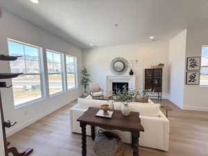 Living area featuring plenty of natural light, a fireplace, light wood-style flooring, recessed lighting, and a textured ceiling