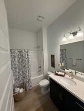 Full bath with vanity, shower / bath combo with shower curtain, and wood finished floors