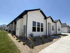 View of side of home featuring board and batten siding, a residential view, and a yard