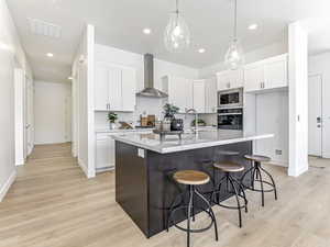 Kitchen featuring tasteful backsplash, a kitchen bar, light wood finished floors, recessed lighting, and white cabinetry