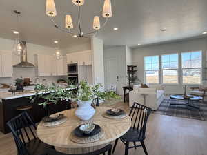 Dining area featuring a textured ceiling, light wood-style flooring, recessed lighting, and a chandelier