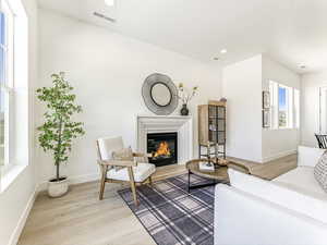 Living area with light wood-style flooring, a glass covered fireplace, and recessed lighting