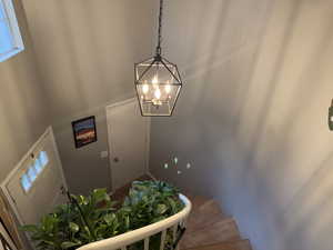 Stairs featuring a chandelier, healthy amount of natural light, and wood finished floors