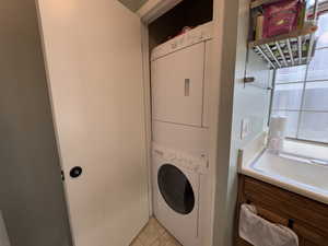 Laundry room with estacked washer and dryer and light tile patterned floors