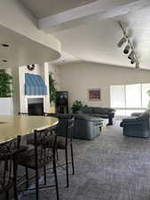 Dining area featuring vaulted ceiling, a textured ceiling, a fireplace, dark colored carpet, and rail lighting