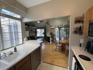 Kitchen featuring stainless steel appliances, light tile patterned flooring, light countertops, a skylight, and a ceiling fan