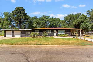 Single story home featuring concrete driveway, a front yard, brick siding, and board and batten siding