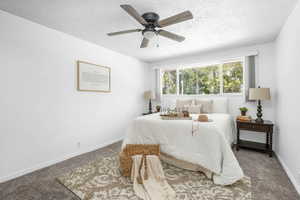 Primary bedroom featuring carpet, a textured ceiling, and a ceiling fan