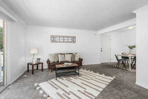 Carpeted living room featuring ornamental molding and a textured ceiling