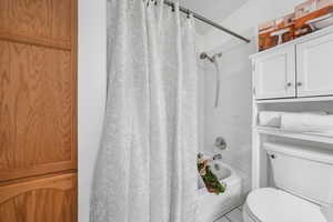 Full bathroom with shower / bath combination with curtain and toilet