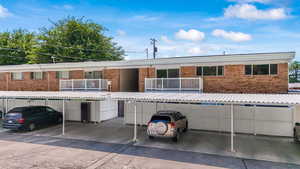 View of front facade (east facing) featuring brick siding and covered parking