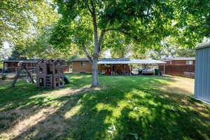 View of yard featuring a playground and a detached carport.