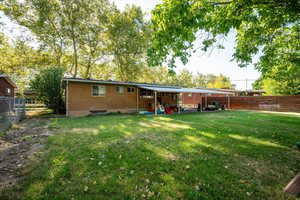 Back of property with brick siding and a fenced backyard.