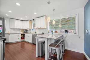 Kitchen featuring dark featuring granite countertops, white painted cabinetry, and Island.