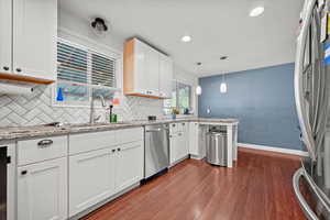 Kitchen with stainless steel appliances, dark wood-style floors, white cabinets, a peninsula, and recessed lighting