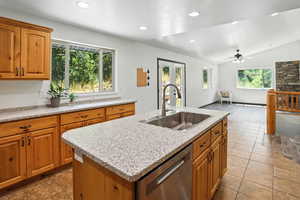 Kitchen featuring plenty of natural light, stainless steel dishwasher, lofted ceiling, a center island with sink, and recessed lighting