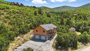 Aerial view of property and surrounding area with a forest and mountains