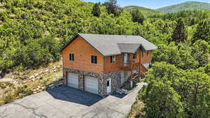View of home's exterior with a forest view, an attached garage, driveway, log veneer siding, and stairway