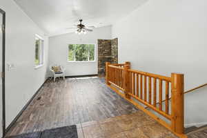 Sitting room with an upstairs landing, lofted ceiling, wood finished floors, and ceiling fan
