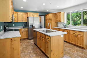 Kitchen featuring an island with sink, recessed lighting, appliances with stainless steel finishes, and light stone counters