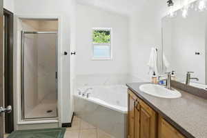 Bathroom featuring vanity, a stall shower, a whirlpool tub, tile patterned flooring, and vaulted ceiling