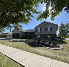 Split level home with brick siding, an attached garage, a front lawn, and concrete driveway