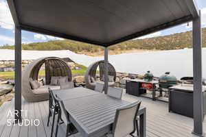 Wooden terrace with a fenced backyard, grilling area, and outdoor dining area