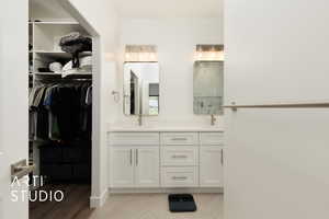 Bathroom with double vanity, a spacious closet, a shower, and wood finished floors