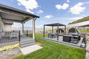 View of green lawn with outdoor dining area, and a separate covered deck with mountain view